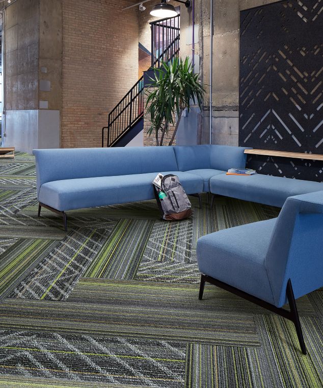 Interface Aglow and Reflectors plank carpet tile in lobby area with blue sectional