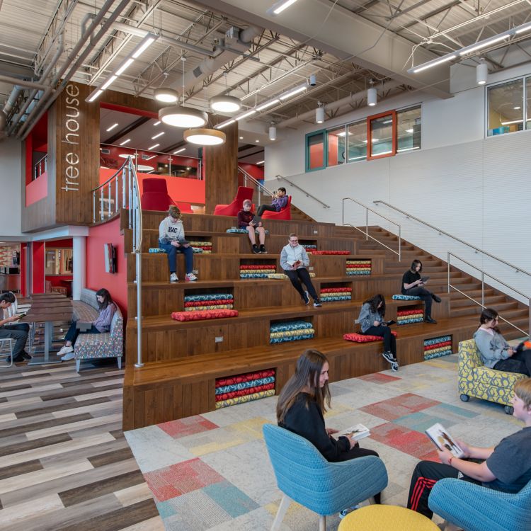 Interface Textured Woodgrains plank LVT with The Standard carpet tile in K-12 library with seating area and stairs