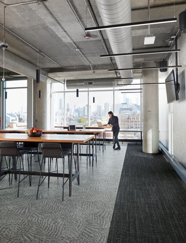 Interface Open Air 401 and 422 carpet tile in dining area with wood tables and man with laptop