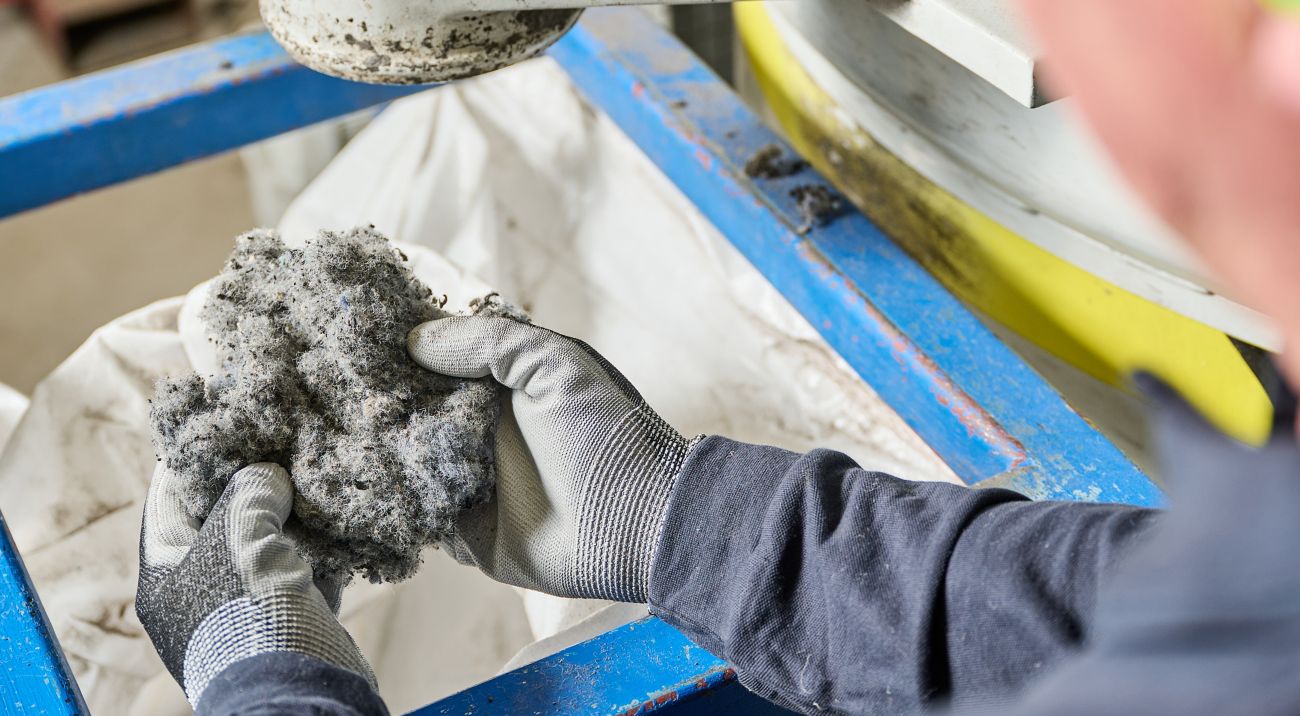Gloved hands examine processed carpet fiber at an Interface recycling facility.
