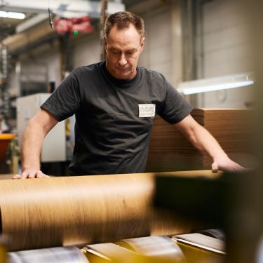 Man rolling rubber flooring and studying in manufacturing facility