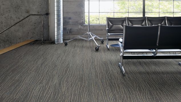 Interface Snow Moon plank carpet tile in waiting area with concrete walls and exposed beams