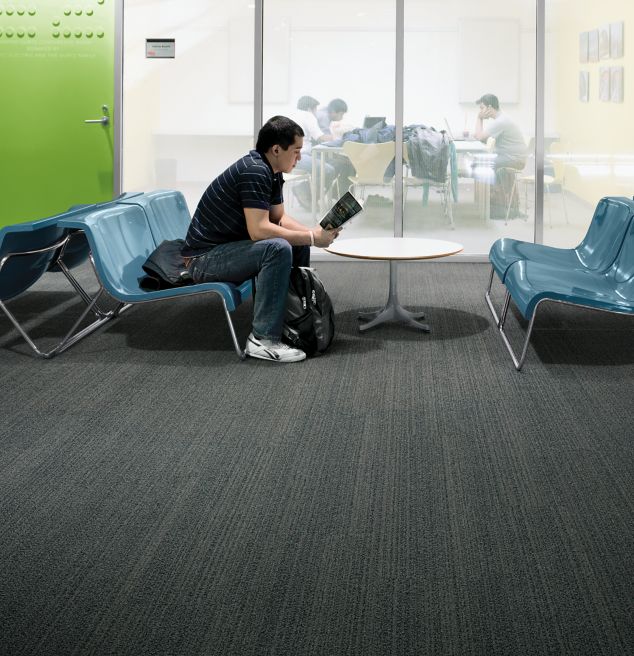 Interface BP410 plank carpet tile with student seated on bench in front of meeting area