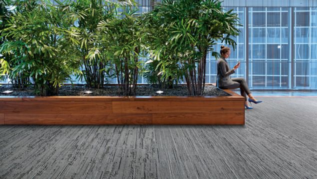 Interface CE171, CE172 and CE173 plank carpet tile in public area with woman seated in front of plants