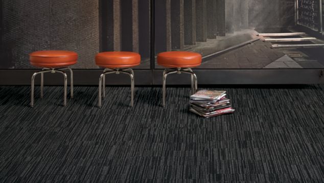 Interface CT102 carpet tile in open area with three red stools and stack of books