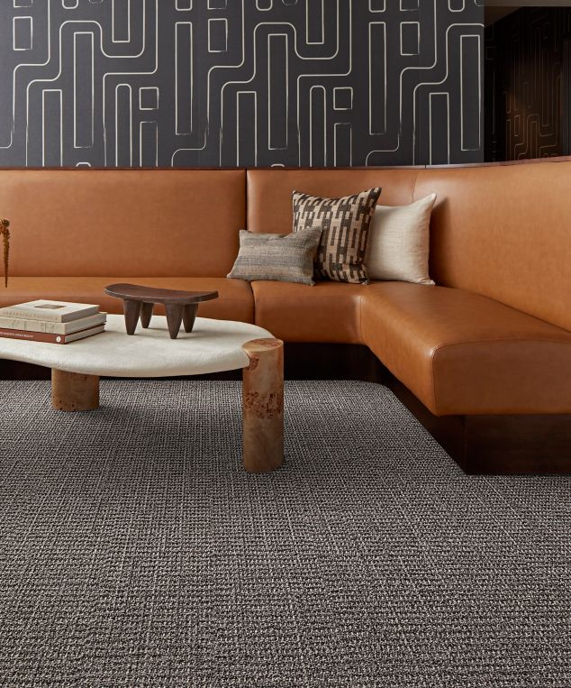 Interface E613 plank carpet tile in corporate lobby with brown wraparound sofa and stone coffee table
