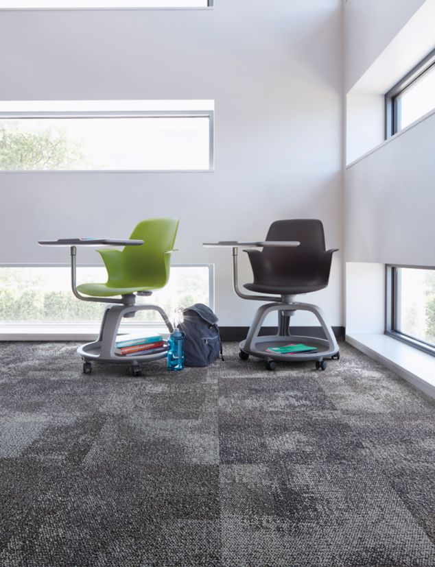 Interface Exposed carpet tile in corner with green and black school desks and horizontal windowns