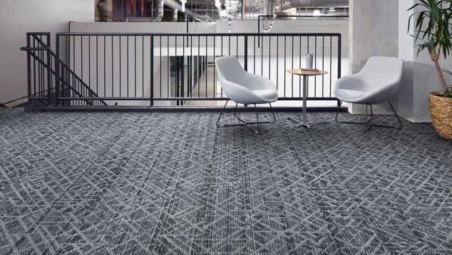 Interface Glisten plank carpet tile in seating area at stairwell with white chairs, small table and plant