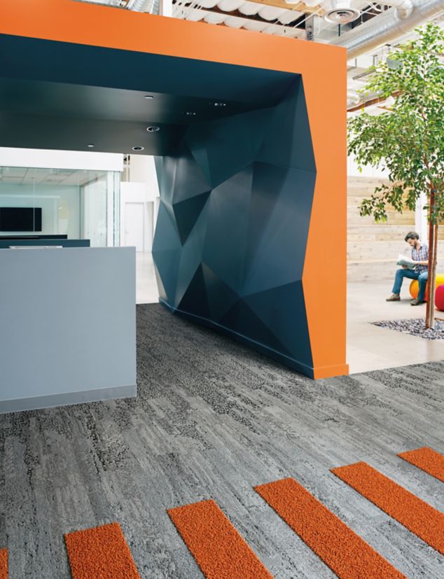 Interface HN810, HN830, HN840 and HN850 plank carpet tiles in blue and orange covered space with man reading on ball chair