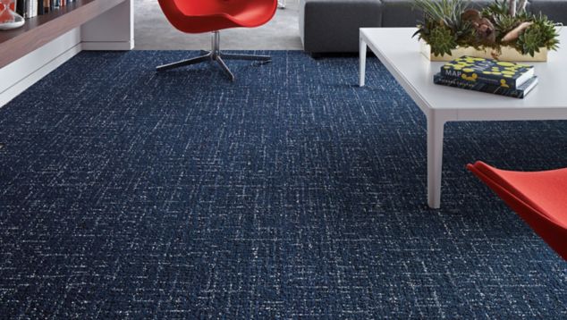 Interface Haptic plank carpet tile in lounge with built in shelves and red chair with Textured Stones LVT in background