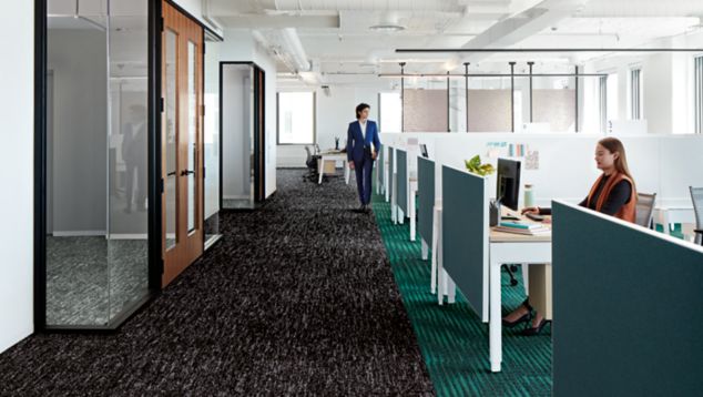 Interface Heart Strings carpet tile in long walkway between workspaces and meeting rooms with woman working at desk