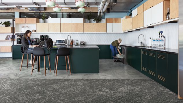 Interface Ice Breaker carpet tile and Textured Stones LVT in kitchen area with women lodaing dish washer and women working on computer