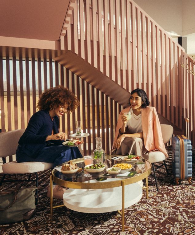 Interface Reeling carpet tile in hospitality lobby with two women chatting and eating