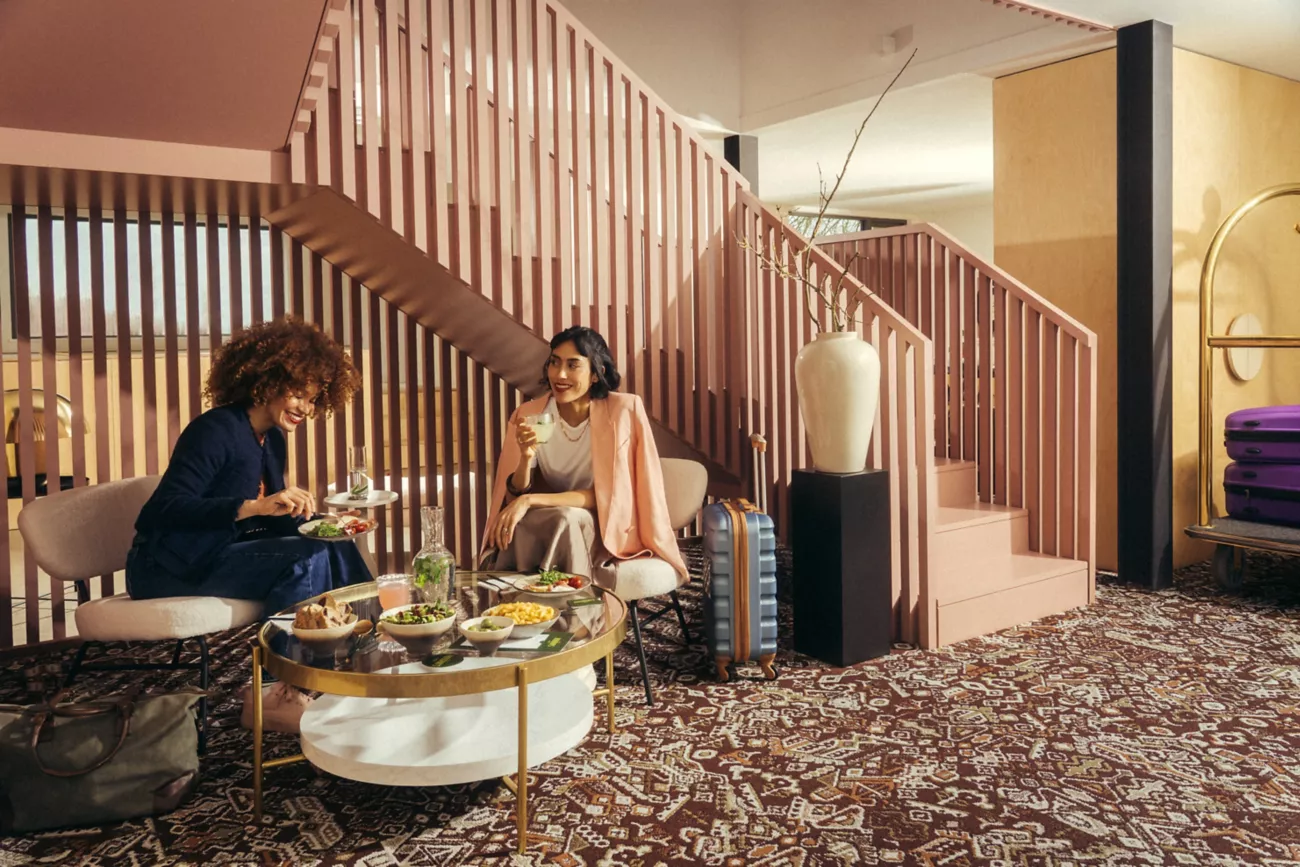 Interface Reeling carpet tile in hospitality lobby with two women chatting and eating