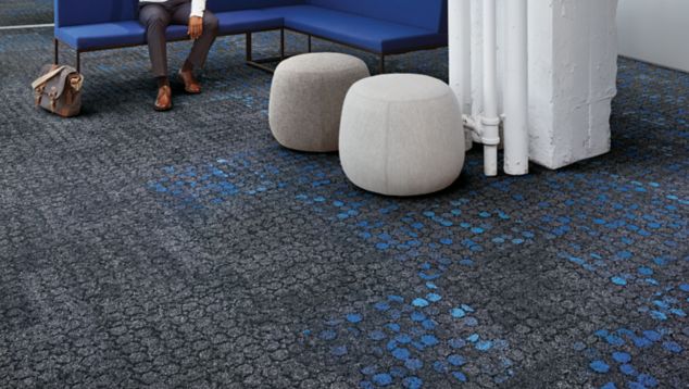 Interface Broome Street and Mercer Street carpet tile in lobby with man seated on blue couch
