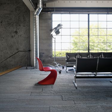 Interface NF400 and NF401 plank carpet tile in public space with black beam seating plus red chair and large window