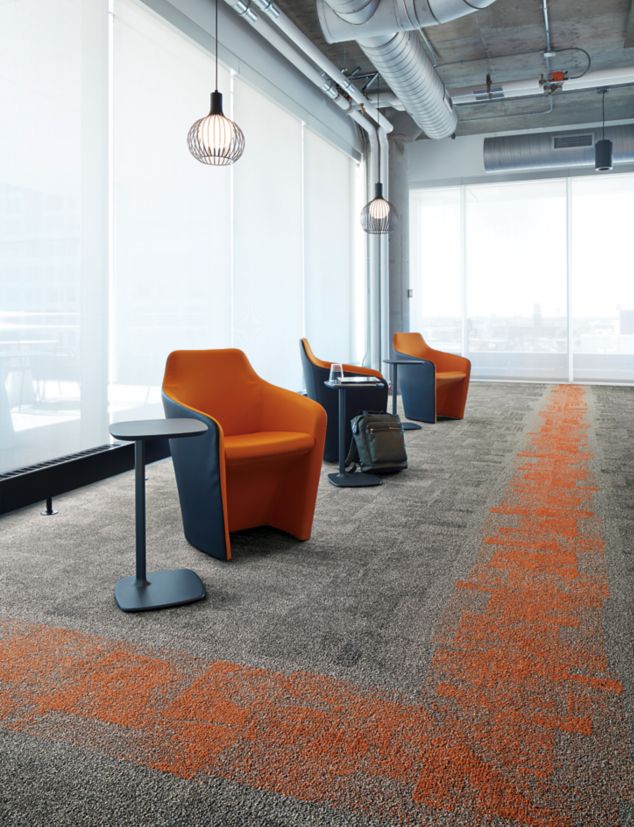 Interface Open Air 404 carpet tile in corner space with open cement ceiling and orange chairs