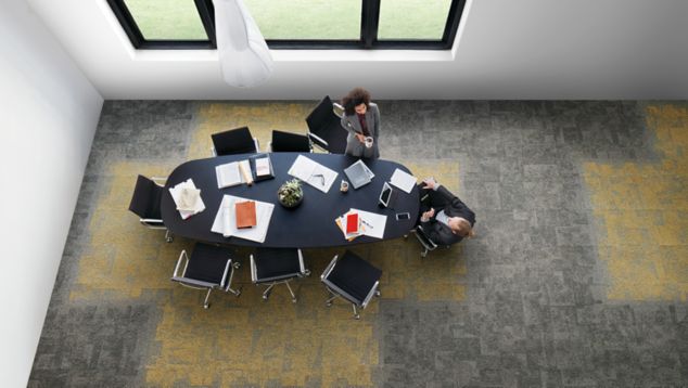 Interface Open Air 404 carpet tile in overhead view of meeting table with man and woman talking and drinking coffee