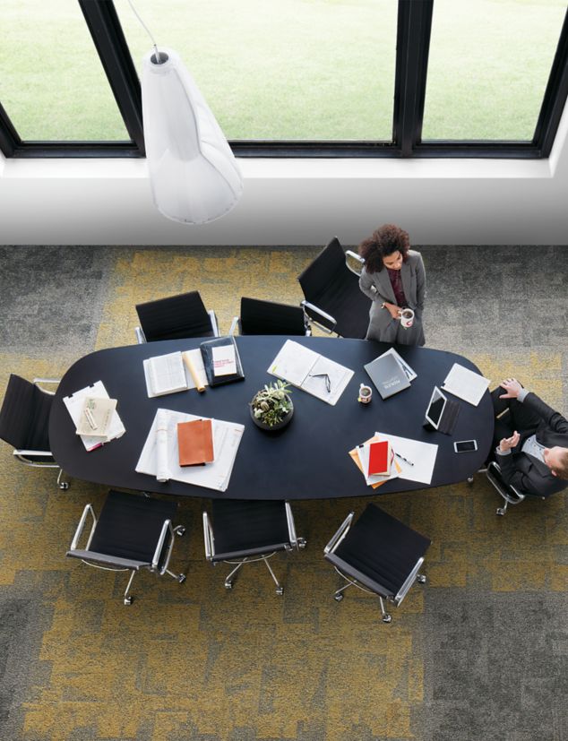Interface Open Air 404 carpet tile in overhead view of meeting table with man and woman talking and drinking coffee