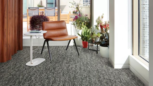 Interface Obligato plank carpet tile with leather chair and potted plants in windows