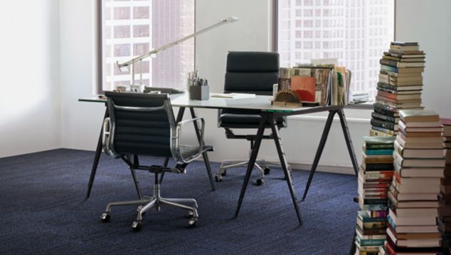 Interface On Line plank carpet tile in corner space with desk and stacks of books against wall