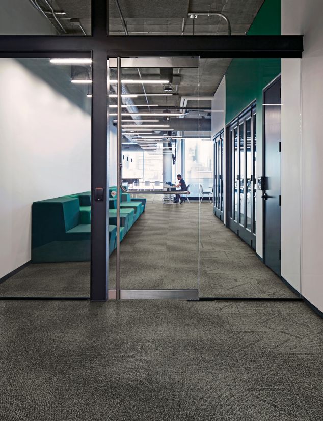 Interface Open Air 416 carpet tile with glass doorway and man working on computer in background