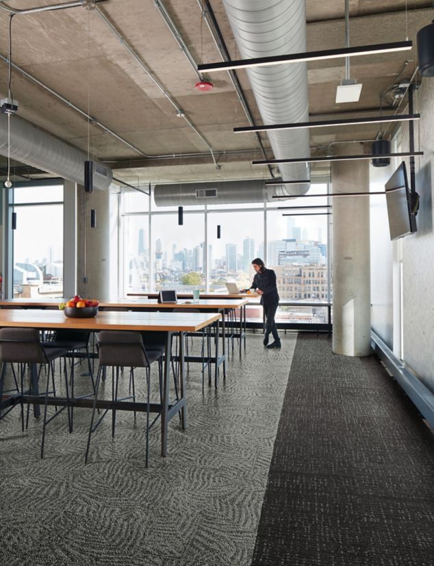 Interface Open Air 422 carpet tile in dining area with open wood tables and man working on laptop at the end