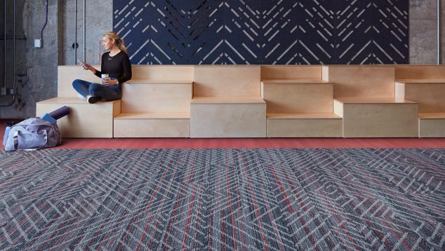 Interface Reflectors plank carpet tile with Studio Set LVT in open area with woman seated on wood risers