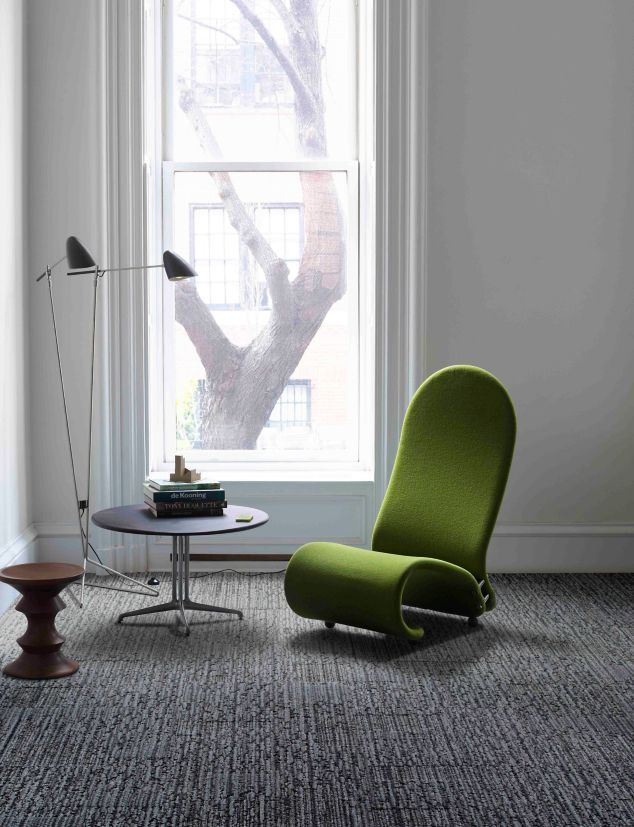 Interface UR201 carpet tile in room with green chair, round table and Eames stool with tall window