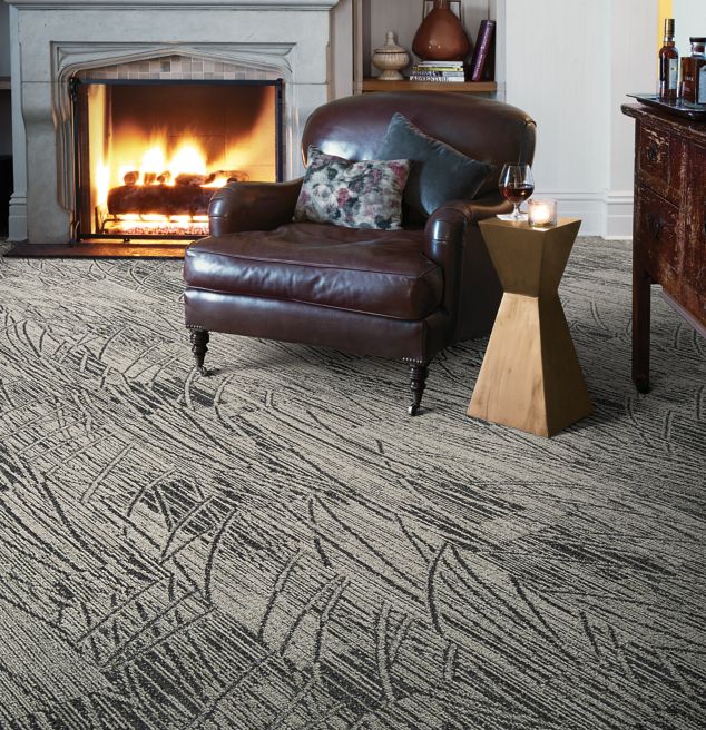 Interface WE152 plank carpet tile in sitting area with fireplace and large leather chair