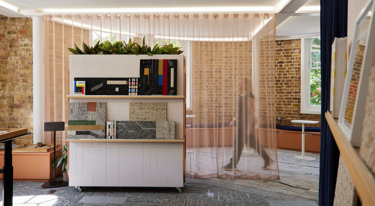 Interface carpet tile samples on display in a showroom with coordinating flooring.